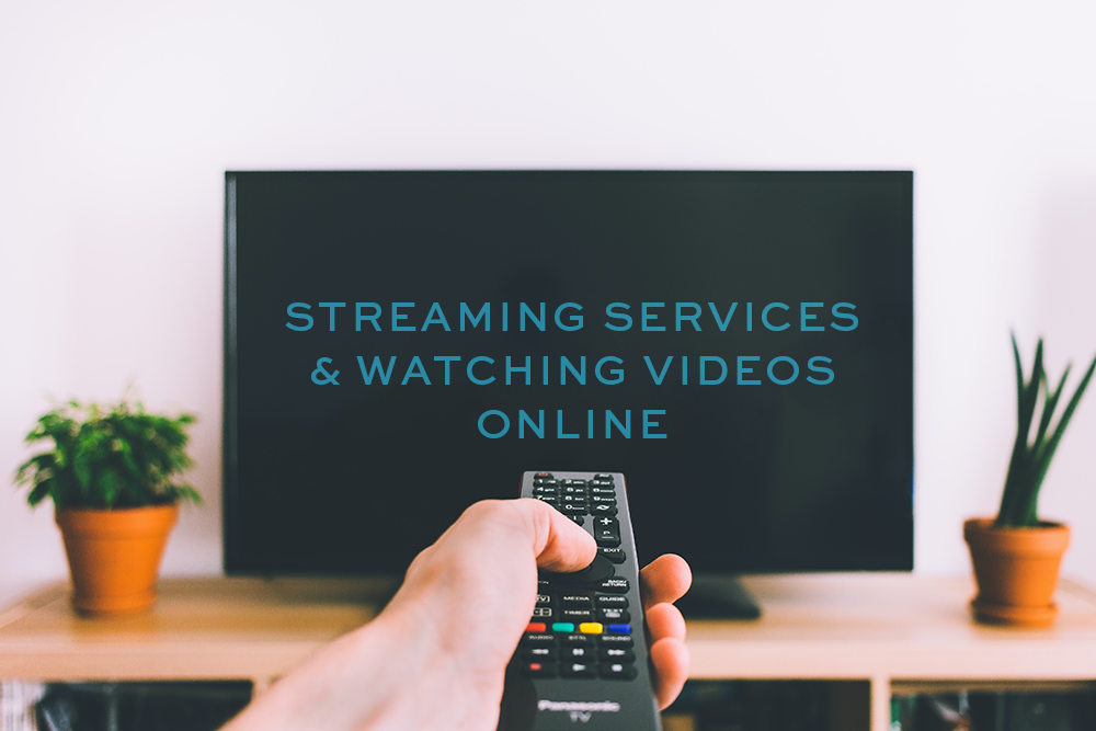 A hand points a remote at a television screen that reads streaming services & watching videos online